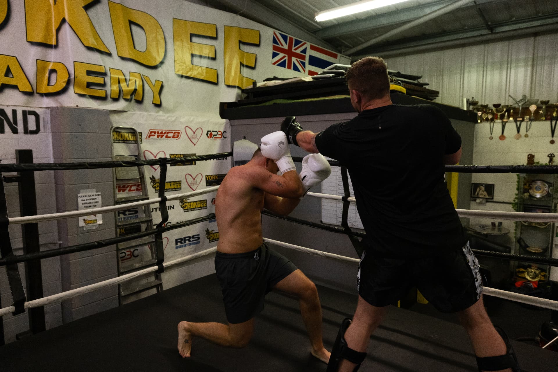 Boxers sparring in the Chokdee ring with the academy logo on the wall