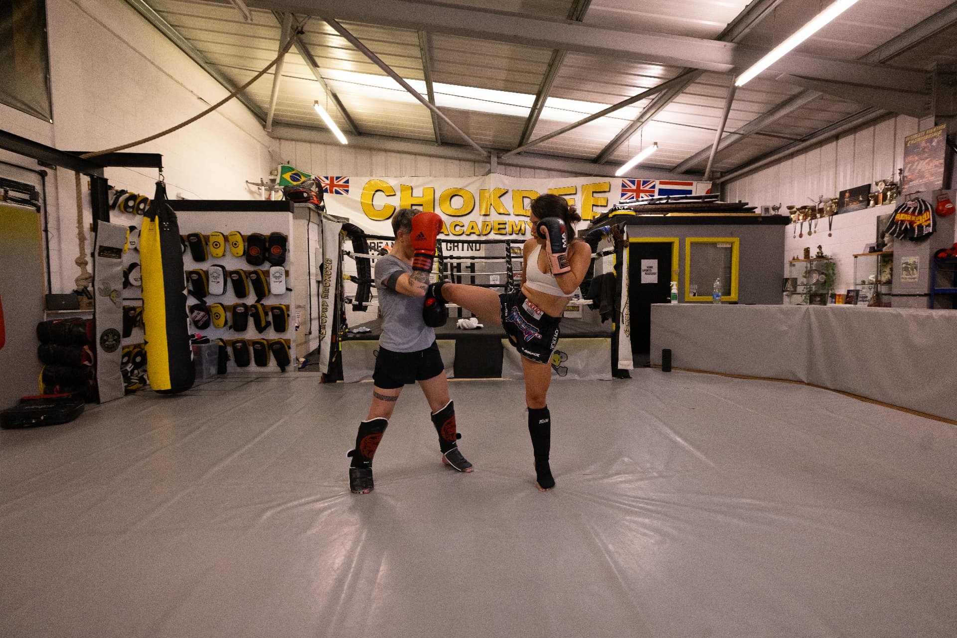 Member throwing a high kick onto pads during Muay Thai training at Chokdee